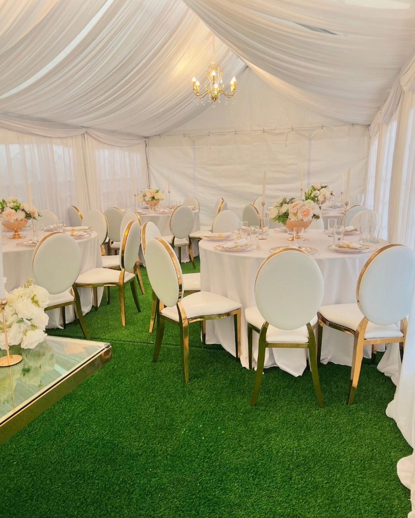 Elegant white marquee interior with gold chairs, draping and chandelier