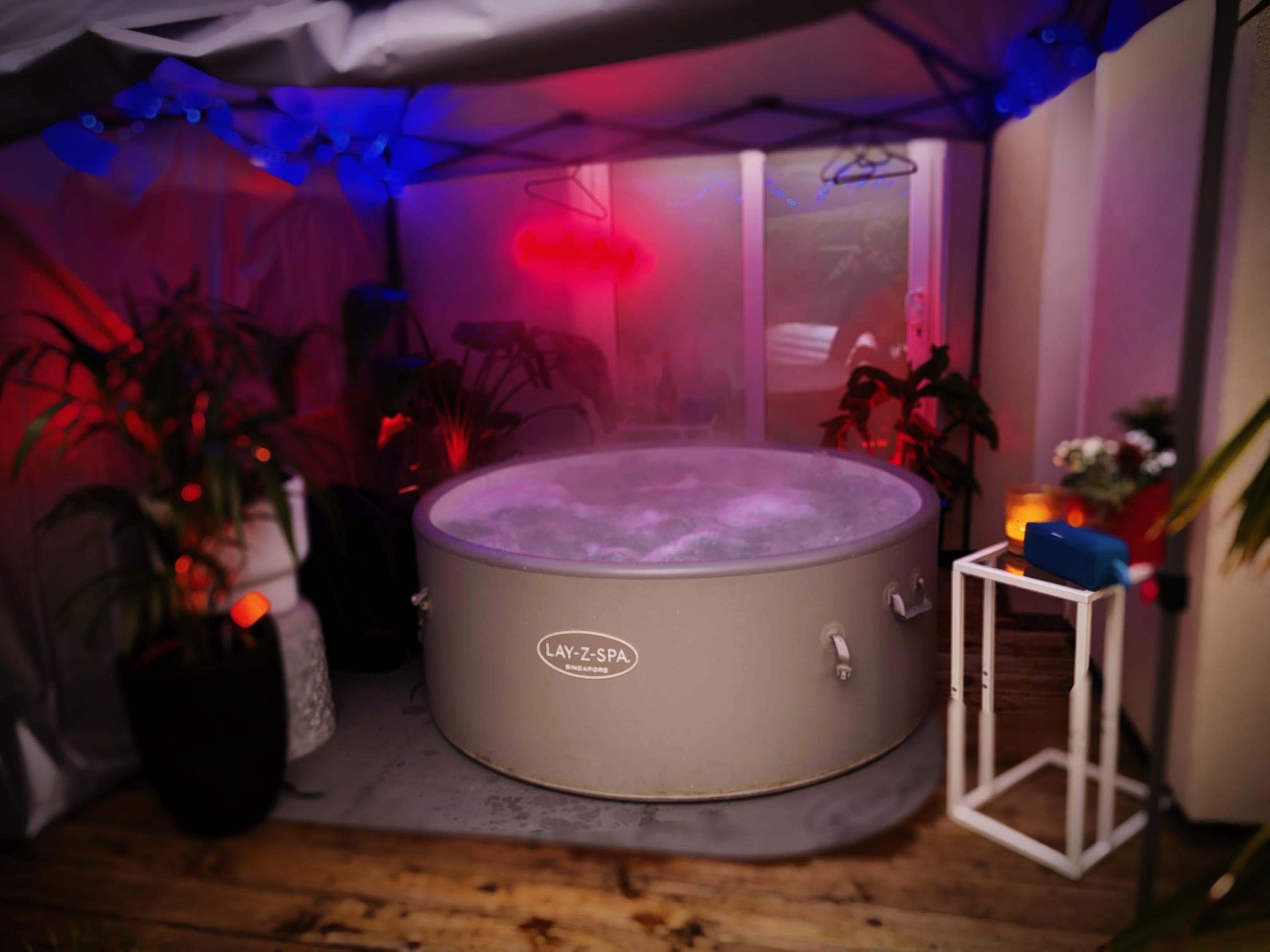 Lay-Z-Spa Singapore hot tub under gazebo with neon lighting, steam and tropical plants