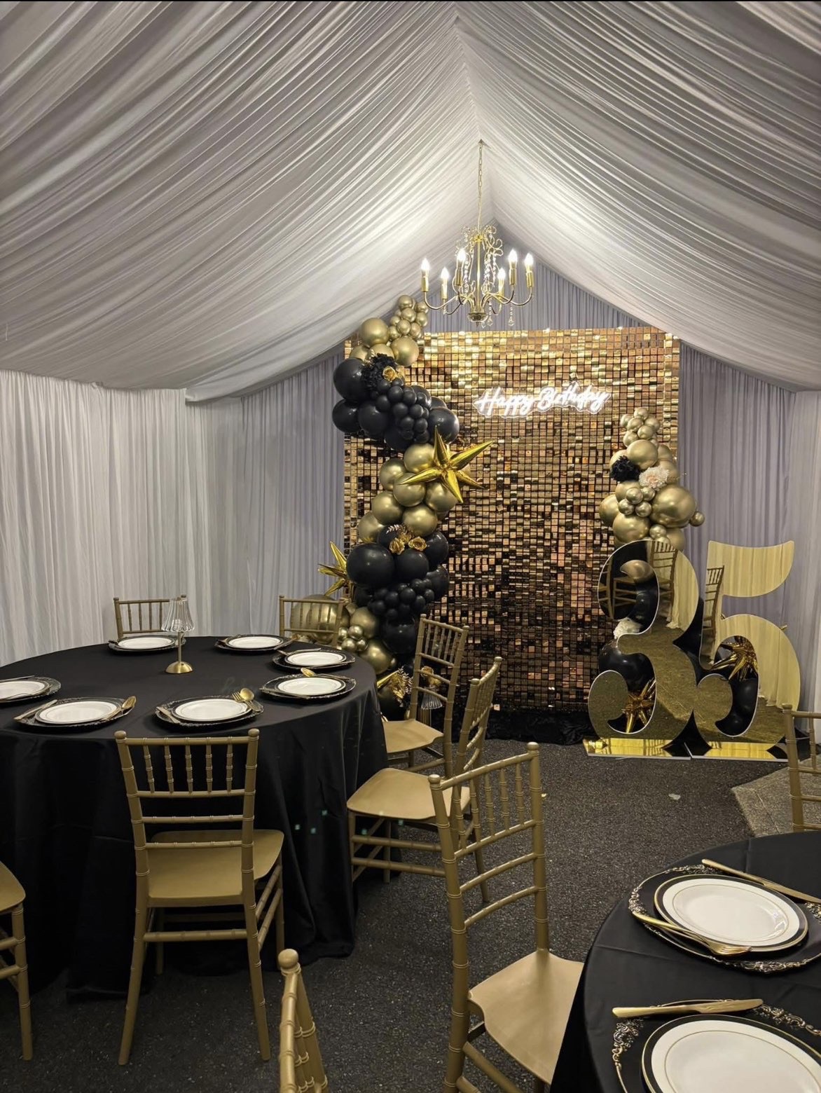 Marquee 35th birthday party with gold sequin backdrop, black and gold balloons and chandelier