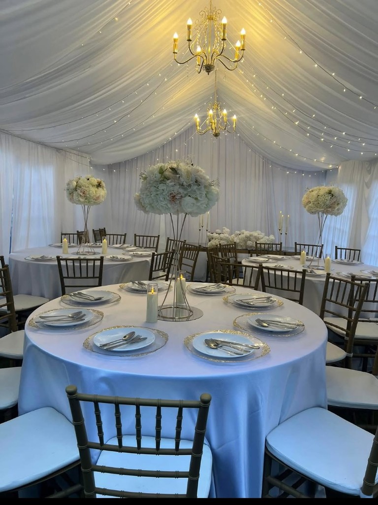 Wedding marquee interior with round tables, chandeliers and fairy lights